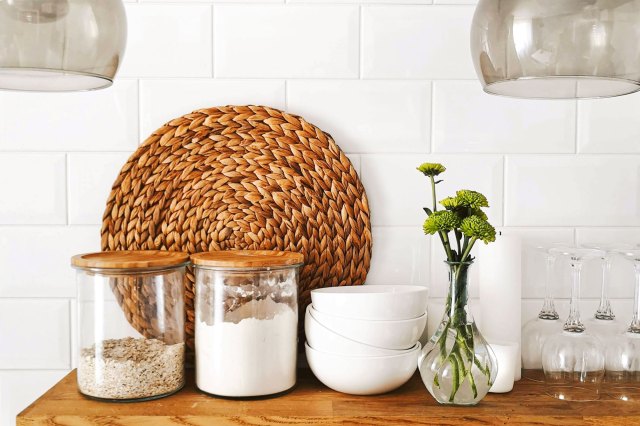 An image of two clear glass jars on brown wooden floating shelf