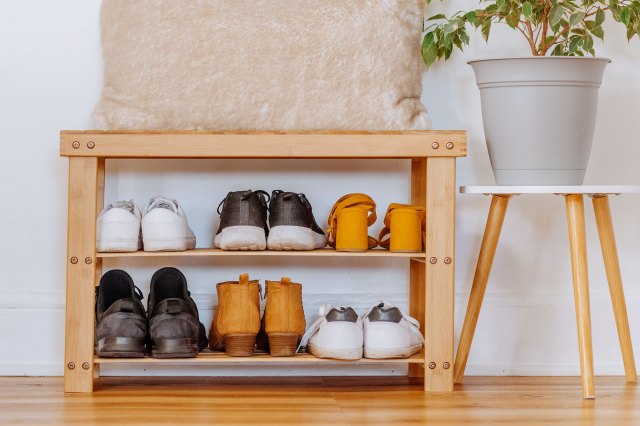 A shoe rack next to a stool with a plant on it