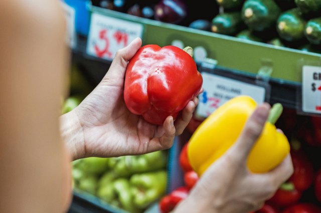 A person holding a red bell pepper and yellow bell pepper in their hands