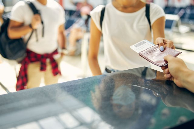 An image of a woman giving a boarding pass to a boarding guard for checking into a flight