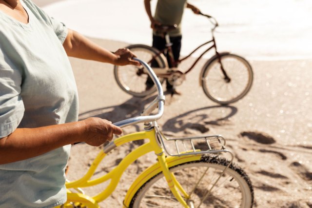 An image of two people riding bikes on the beach