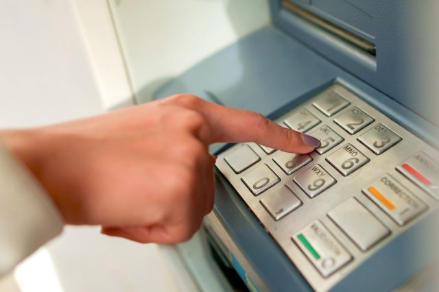 An image of a person punching numbers into an ATM