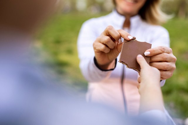 An image of a woman breaking off a piece of a chocolate bar