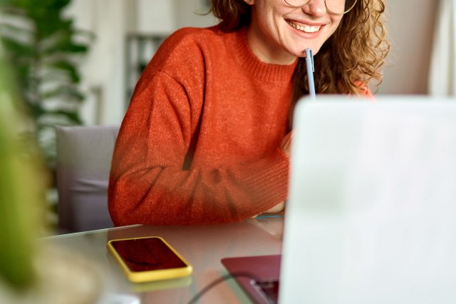 An image of a woman sitting at a desk looking at a computer screen