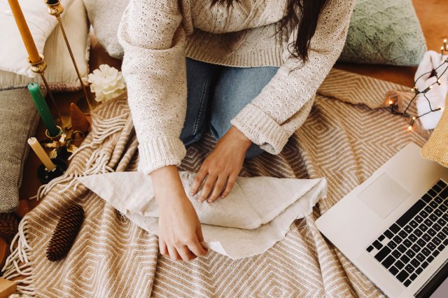 An image of a woman in cozy sweater wrapping gift in fabric