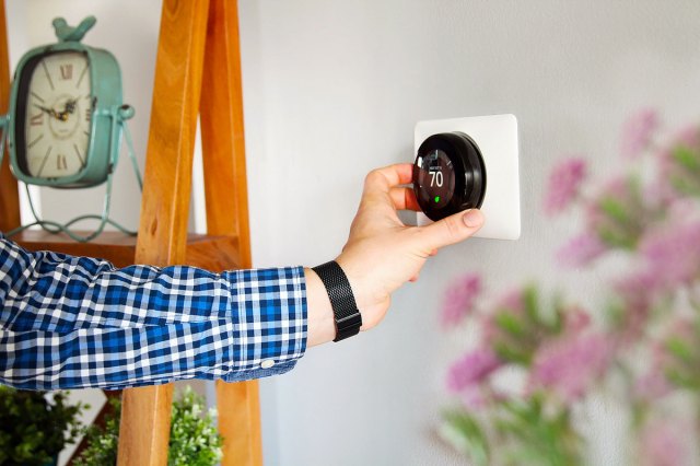 An image of a person adjusting a smart thermostat