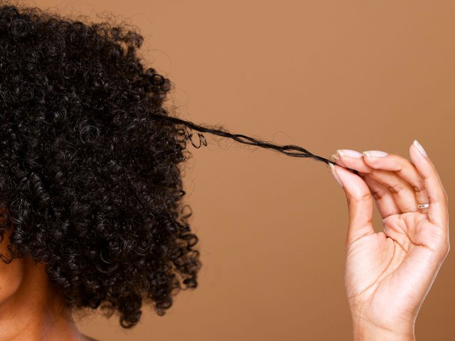 An image of a woman holding out strands of hair from her head