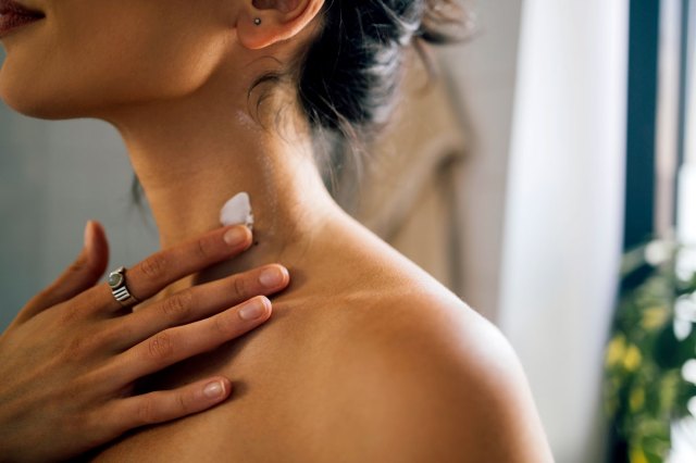 An image of a woman putting cream on her neck