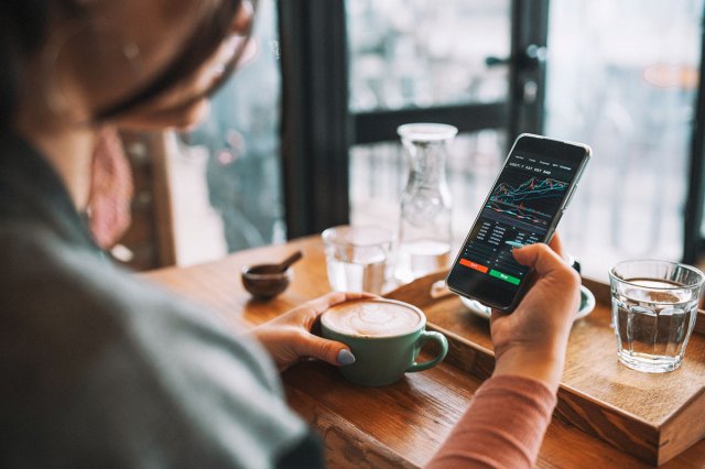 An image of a woman looking at stocks on her phone