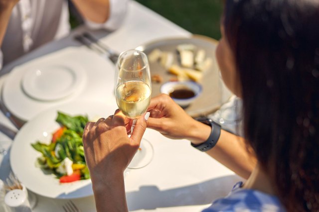 An image of a woman sitting at a table holding a glass of champagne