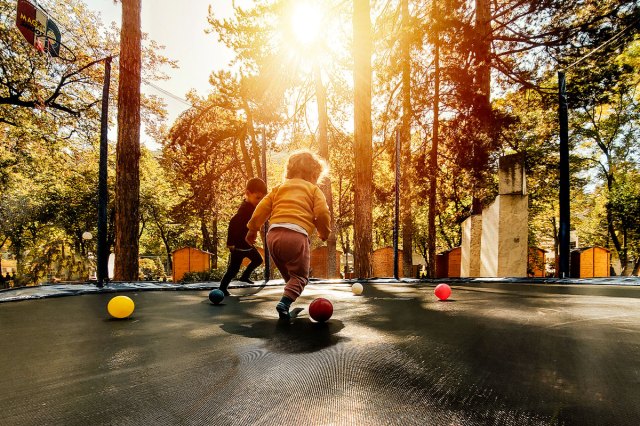 An image of two kids playing on a trampoline