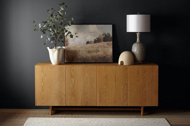 An image of a wooden credenza against a wall painted in Cracked Pepper by Behr