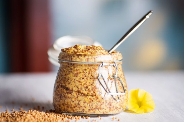 An image of a jar of mustard with a spoon in it