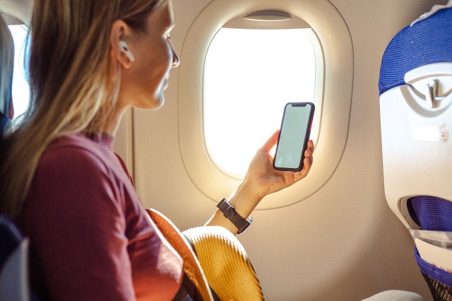 An image of a woman sitting on a plane, looking at her phone