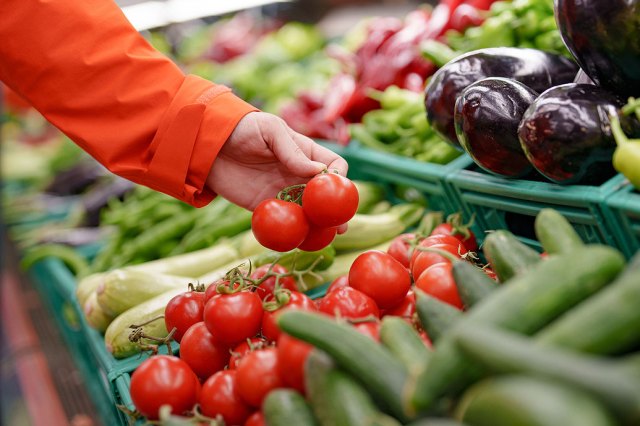 An image of a person selecting tomatoes from the produce section