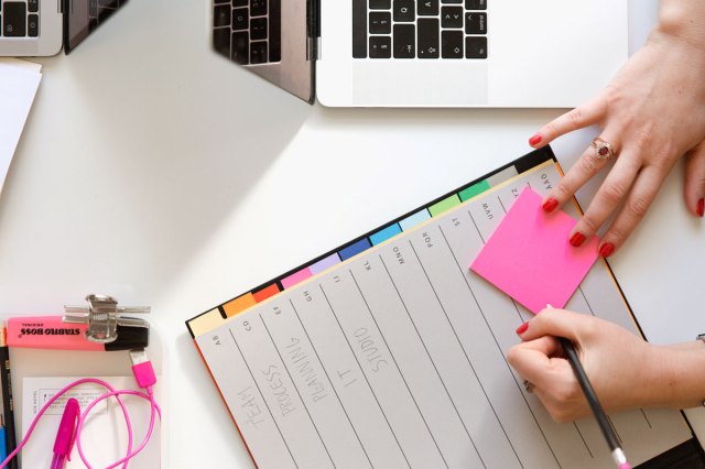 An image of a person holding pencil and writing in a planner