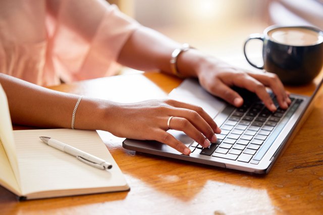 An image of a woman typing on a laptop