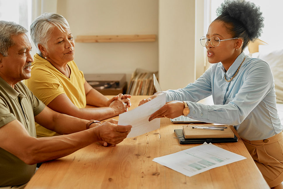 An image of a man and a woman sitting at a table and talking to a female financial advisor