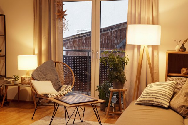 An image of a warm, light cozy living room in winter with a snowstorm outside