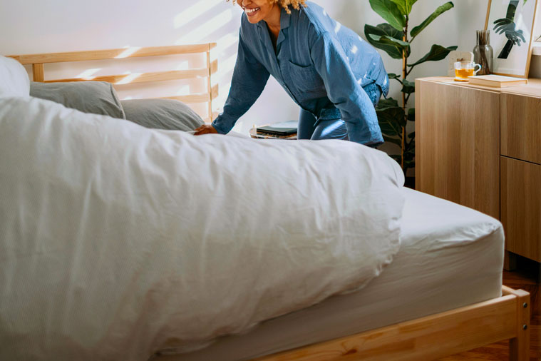 An image of a woman making the bed