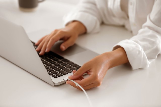 An image of a person attached a power adapter to a laptop