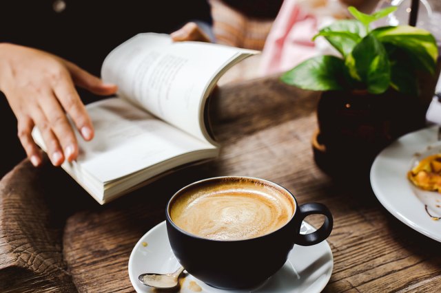 An image of a person reading a textbook at a coffee shop