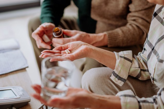 A close-up image of senior man giving his wife medication at home