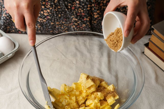 An image of a person pouring brown sugar into a bowl of butter