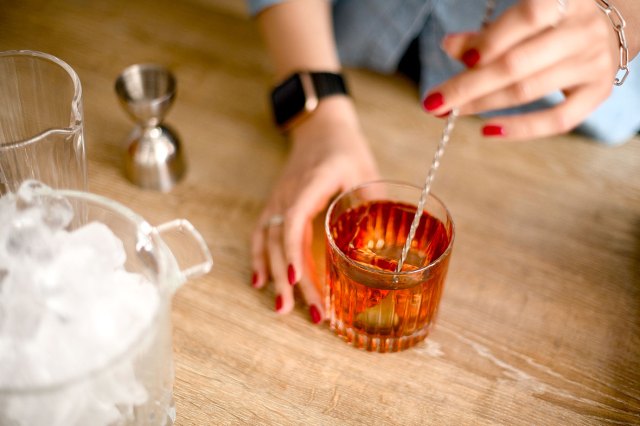 An image of a woman stirring a red alcoholic beverage