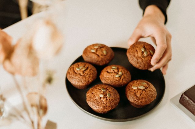 An image of a hand taking a muffin off a plate of muffins