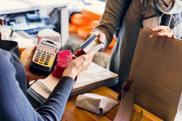 An image of a shopper handing their credit card to a store worker behind a counter