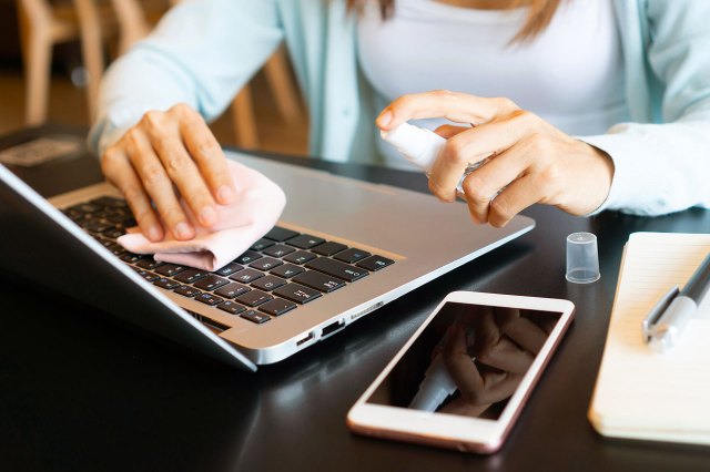 An image of a woman cleaning her laptop