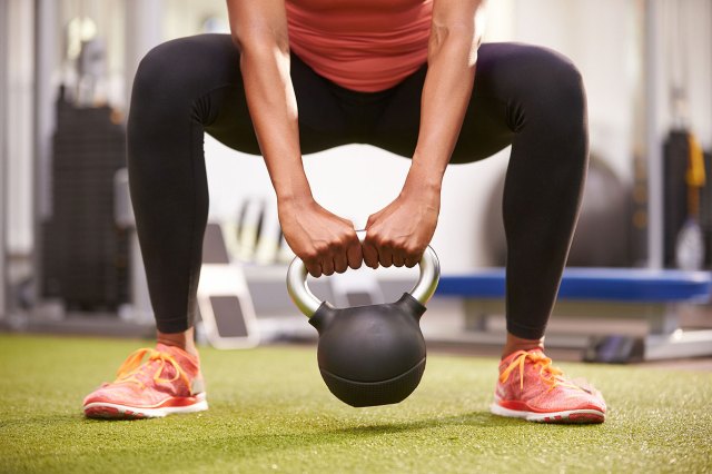 An image of a woman lifting a kettle bell