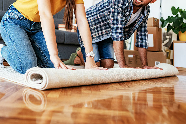 An image of a woman and man rolling out a rug