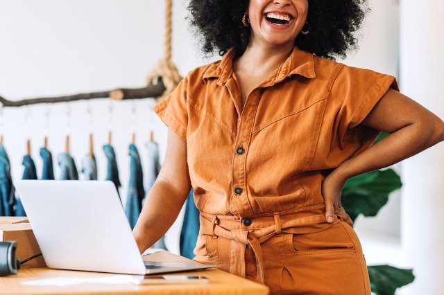 An image of a woman laughing in front of a laptop