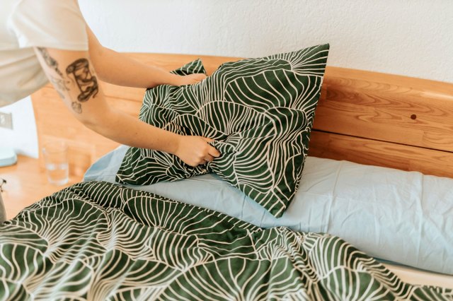 An image of a person making a med with green and white bedding