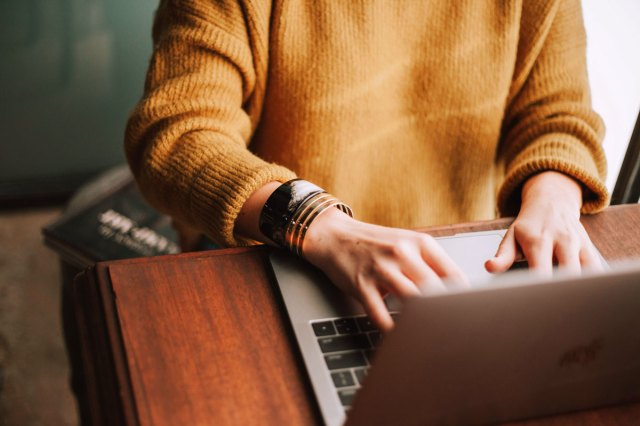 An image of a woman typing on a laptop