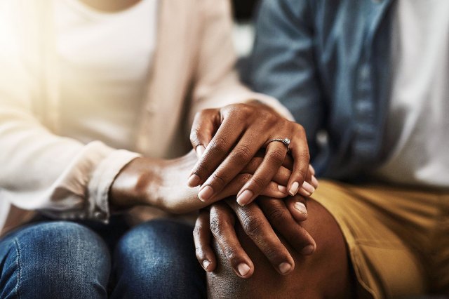 An image of a woman's hands on a man's knee