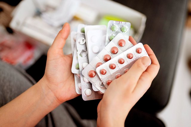 An image of hands holding sleeves of pills