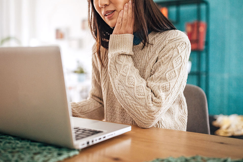 An image of a woman at the computer with her hand on her jaw