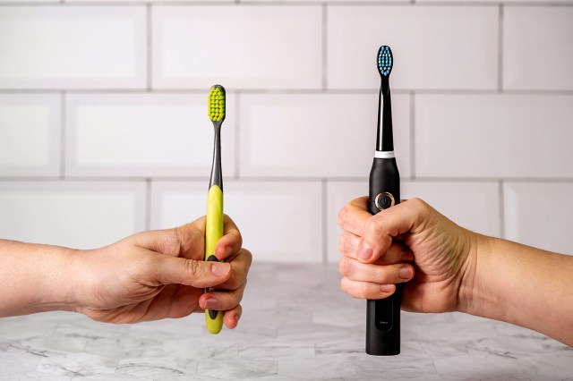 An image of two hands holding toothbrushes