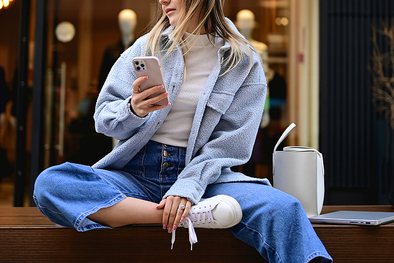 An image of a woman holding a phone sitting on a table