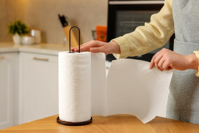 An image of a person ripping a piece of paper towel from a roll