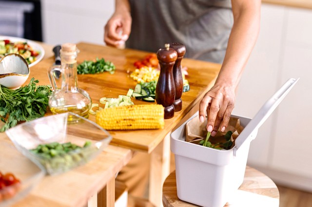 A woman puts food in a compost bin