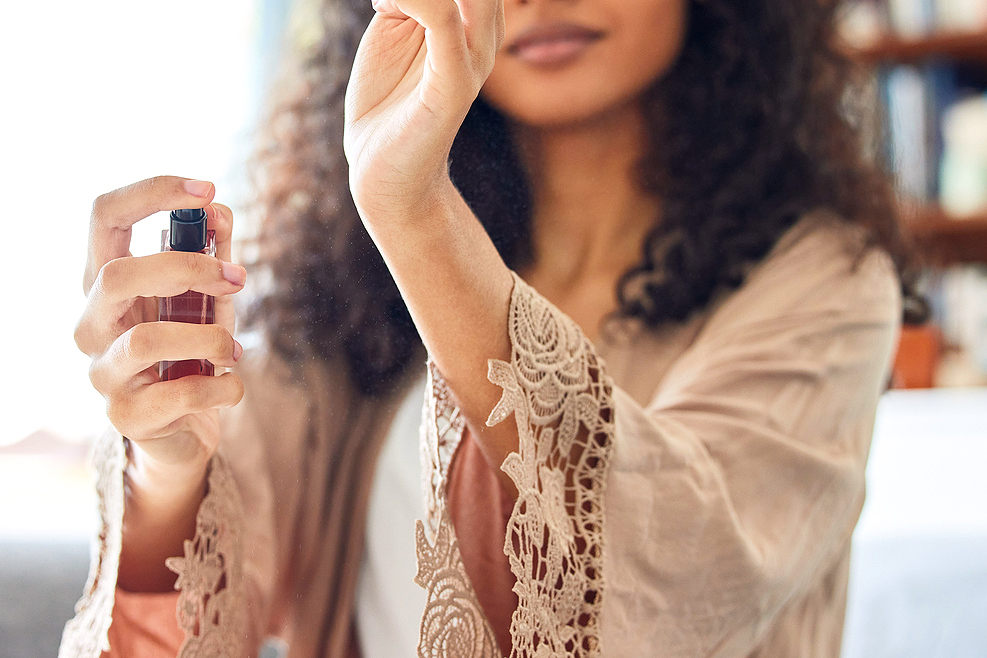 An image of a woman spraying perfume on her wrist