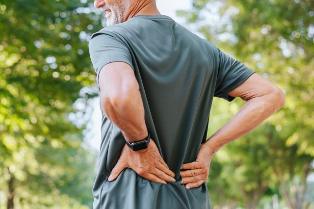 An image of a man outside with his hands on his back