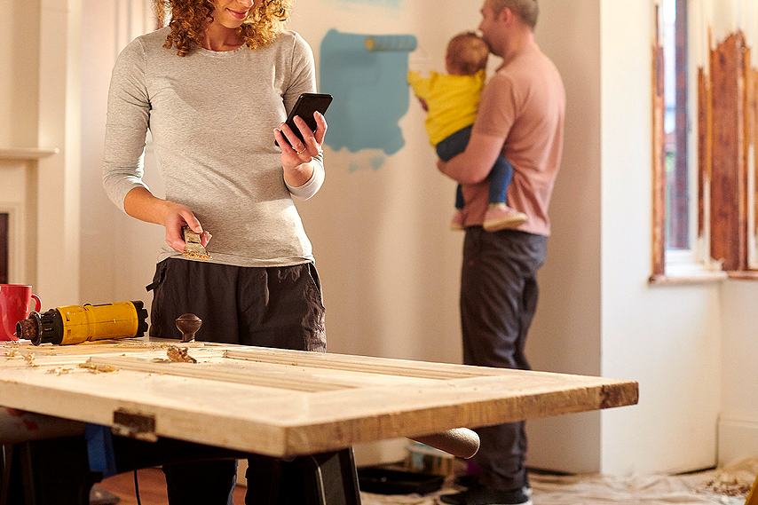 An image of a woman looking at her phone in a room that is being rennovated