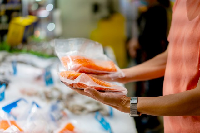 An image of a man holding two packages of salmon