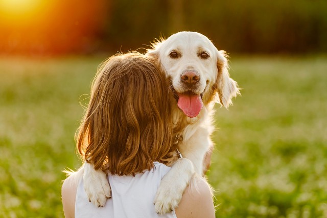 An image of a woman holding a dog outside