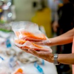 Person holding two packaged salmon filets